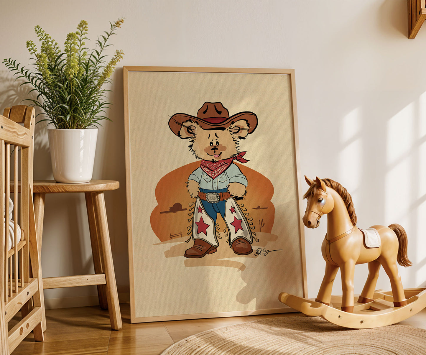 Framed cowboy bear print on a wall with a rocking horse and plant in the background.