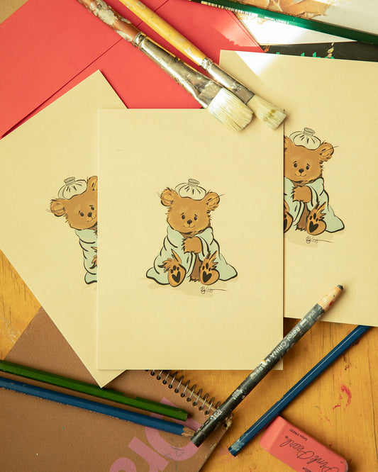Vintage-inspired "Get Well Soon" card featuring a hand-drawn Pola Bear character wrapped in a cozy blue blanket with an ice pack balanced on his head. Art by Robert John Kley.